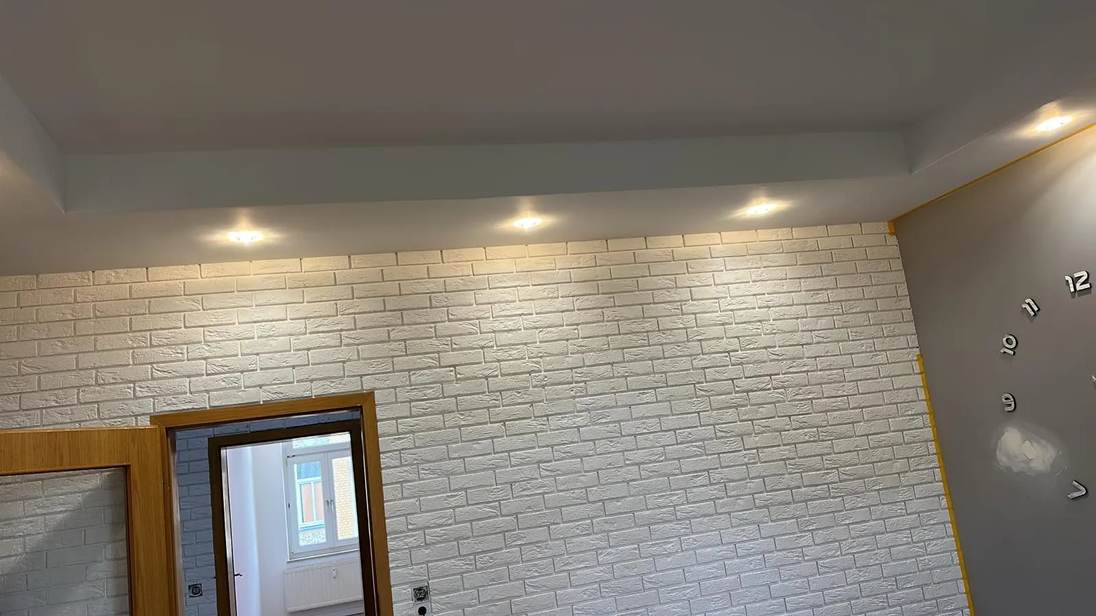 Wohnraum mit abgehängter Decke, Deckenspots und verblendeter Ziegeloptik-Wand